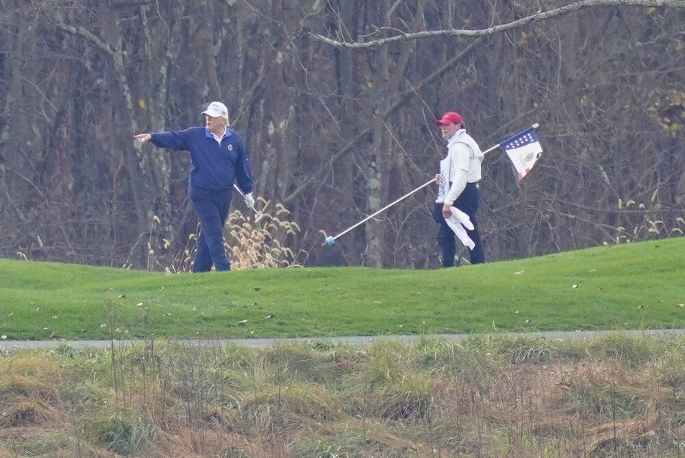 President Donald Trump, left, gesturing while playing golf at Trump National Golf Club in Sterling, Va.